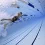 Visualizing how flutter kick vertical vortices generate propulsion and suppress body sway in swimmers